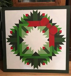 a green and red christmas wreath on a white background with a red bow hanging from it's center