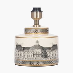 a white and gold jar with a building on the front, surrounded by black and white designs