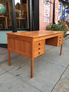 a wooden desk sitting on the side of a street next to a building with windows