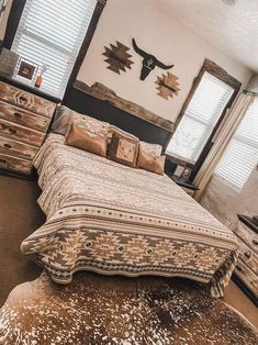 a bed sitting in a bedroom next to two windows and a cowhide rug on the floor