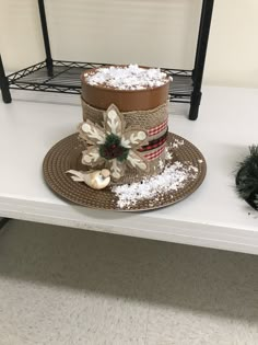 a hat with snow on it sitting on top of a white table next to a potted plant