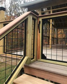 a wooden deck with black iron railing and wood steps