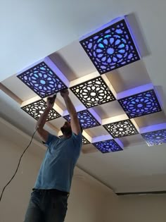 a man that is standing on a ladder in front of a ceiling with blue lights