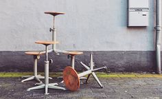 three wooden stools sitting on top of each other in front of a gray wall