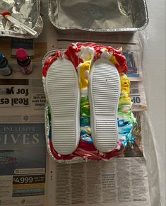 two pairs of white slippers sitting on top of a newspaper next to other items