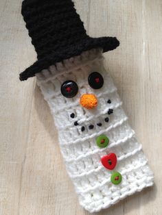 a crocheted snowman with a black hat and button eyes on it's face