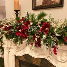 a fireplace mantel decorated with greenery and red flowers