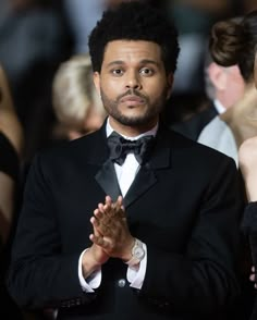 a man in a tuxedo standing with his hands folded