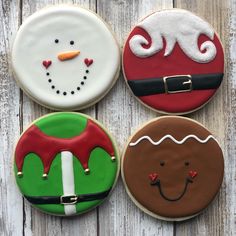 four decorated christmas cookies sitting on top of a wooden table