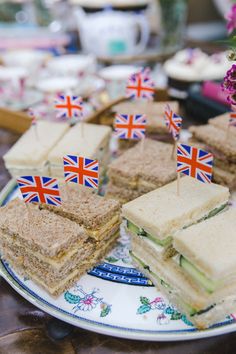 sandwiches with british flags on them are sitting on a blue and white plate next to purple flowers