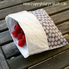 a bag filled with raspberries sitting on top of a wooden table