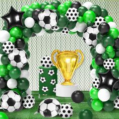 a bunch of balloons and soccer balls around a trophy