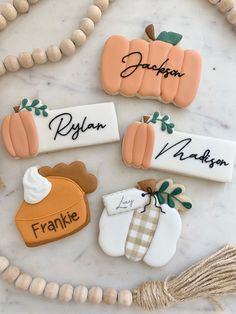 decorated cookies with names and pumpkins are on a marble countertop next to beads