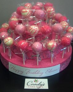 pink and white cake pops are arranged on top of a pink stand with clear plastic wrappers