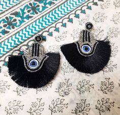 Be protected from the evil eye when you wear these stylish Hamsa beaded hand earrings, Hand of Fatima. The Hand is outlined in sparkly beads. Beads are sewn in, not glued. The fringe adds a lovely shape to the earring. Lightweight and comfortable to wear due to fabric backing. find even more great earrings here: https://www.etsy.com/shop/boutiquebymaryam?section_id=22797814 Be sure to view the rest of my shop here: https://www.etsy.com/shop/boutiquebymaryam All my jewelry is boxed and wrapped to Black Bohemian Jewelry With Evil Eye, Bohemian Evil Eye Jewelry For Party, Black Bohemian Evil Eye Jewelry, Traditional Tassel Earrings With Beaded Fringe As Gift, Traditional Beaded Fringe Tassel Earrings As Gift, Bohemian Evil Eye Earrings As Gift, Traditional Black Tassel Earrings, Traditional Fringe Earrings For Gift, Hamsa Hand Jewelry