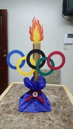 the olympic symbol is on display in front of a wall with a fire coming out of it