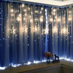 a window with blue curtains and stars on the sheer curtain, along with a vase filled with flowers