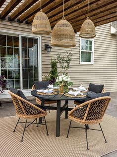 an outdoor dining area with wicker chairs and rattan table, hanging lights over the patio