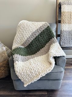 a couch with a blanket on top of it next to a basket full of blankets