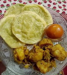 some food is on a glass plate with sauces and an orange in the background