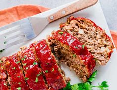 sliced meatloaf with ketchup and parsley on plate next to knife