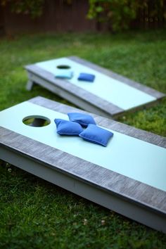 two cornhole game boards with blue bows on them sitting in the middle of grass