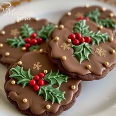 three decorated cookies on a white plate with holly and mistlet decorations, one is chocolate