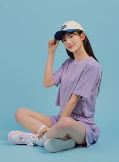 a young woman sitting on the ground wearing a purple shirt and white socks with her legs crossed