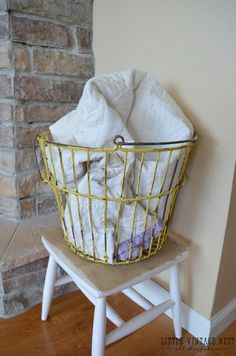 a basket that is on top of a stool next to a brick wall and fireplace