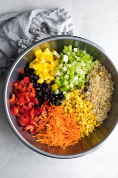 a metal bowl filled with chopped vegetables and rice next to a napkin on the side