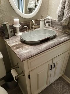 a bathroom with a sink, mirror and toilet paper roll on the counter in front of it