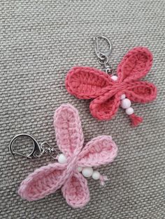 two crocheted keychains with flowers attached to them on a gray surface