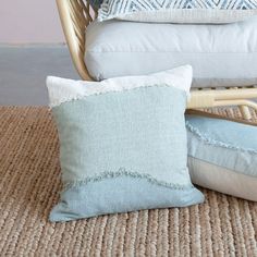 some pillows are sitting on the floor next to a wicker chair