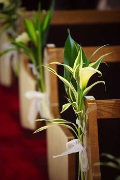 flowers in vases sitting on the pews at a church