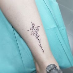 a small cross and flower tattoo on the left leg by a woman's foot