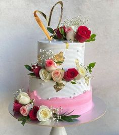 a three tiered cake with flowers and scissors on top is decorated in white, pink, and red