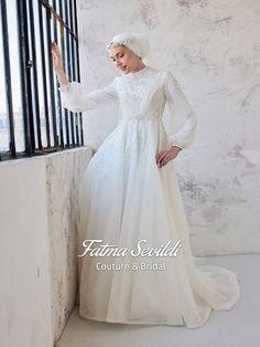 a woman in a white wedding dress leaning against a wall with her hand on the window sill