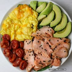 a white plate topped with meat, eggs, tomatoes and avocado wedges