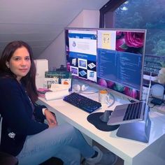 a woman sitting in front of a computer desk with a monitor and keyboard on it