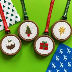 three cross stitch christmas ornaments on green background