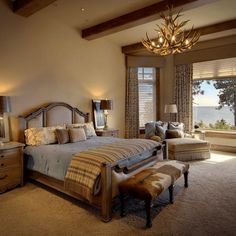 a bedroom with a large bed sitting under a chandelier next to a window