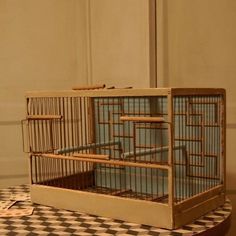 a bird cage sitting on top of a checkered table