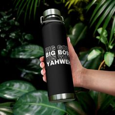 a person holding a black and silver water bottle in front of green leaves with the words big boy, his name yahwe on it