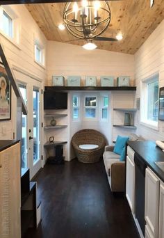 the interior of a tiny house with wood flooring and white walls, black countertops