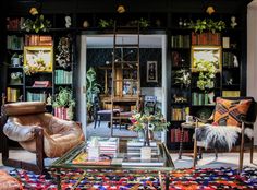 a living room filled with furniture and bookshelves full of shelves covered in plants