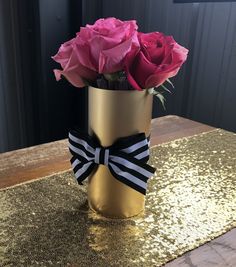 a gold vase with pink roses in it