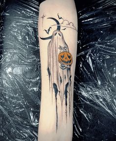 a black and white photo of a halloween themed tattoo on the arm with a pumpkin hanging from it's side