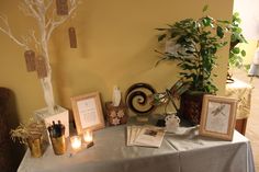 a table topped with pictures and candles next to a tree on top of a table