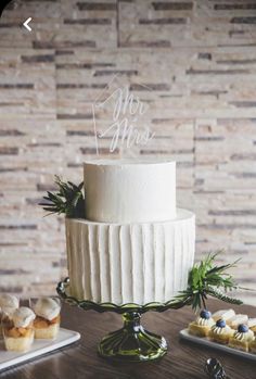 a white wedding cake sitting on top of a wooden table