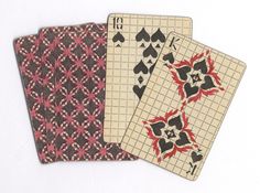 three playing cards with different designs on them, one is red and the other is black